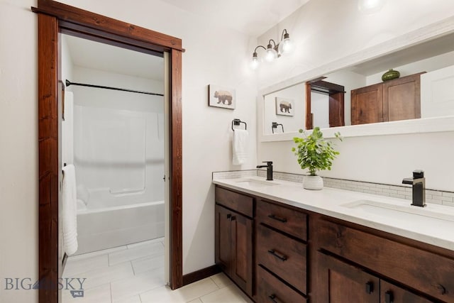 bathroom featuring bathtub / shower combination, a sink, decorative backsplash, and double vanity