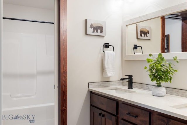 full bathroom featuring double vanity, tasteful backsplash, and a sink