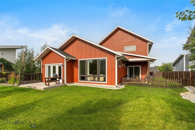 rear view of property with a patio area, fence, board and batten siding, and a yard