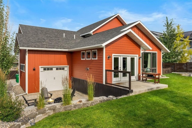 rear view of property with an attached garage, a shingled roof, fence, a yard, and french doors