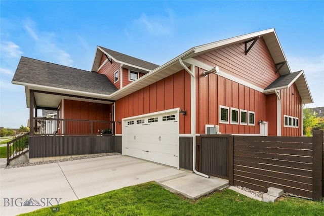 view of side of property featuring a garage, driveway, board and batten siding, and fence