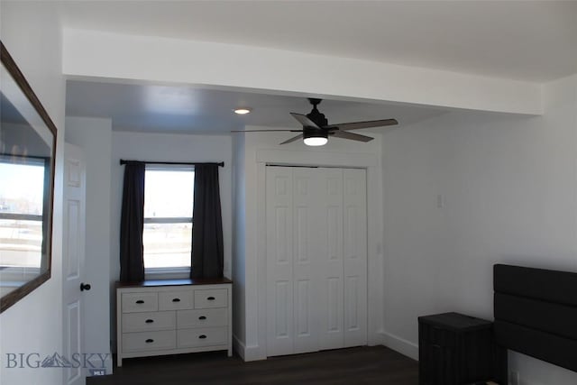 unfurnished bedroom with dark wood-type flooring, a closet, ceiling fan, and baseboards