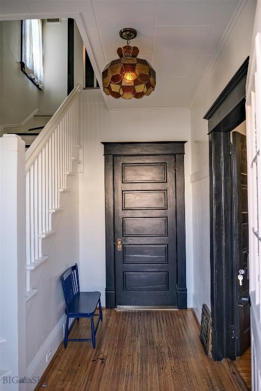 doorway featuring stairs, ornamental molding, dark wood-style flooring, and baseboards