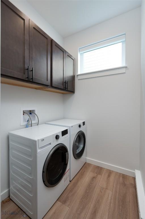 laundry area with cabinet space, baseboards, baseboard heating, washer and dryer, and light wood-type flooring