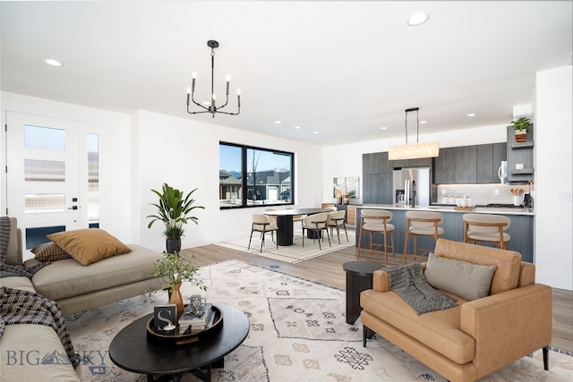 living room with recessed lighting, light wood-style flooring, baseboards, and an inviting chandelier