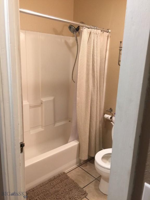 full bathroom featuring shower / bath combo with shower curtain, tile patterned flooring, and toilet