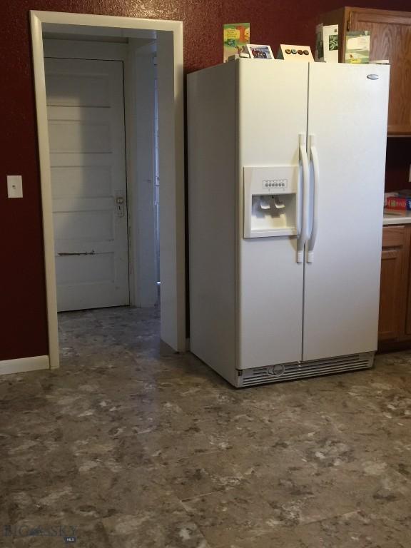 kitchen featuring white fridge with ice dispenser and brown cabinetry