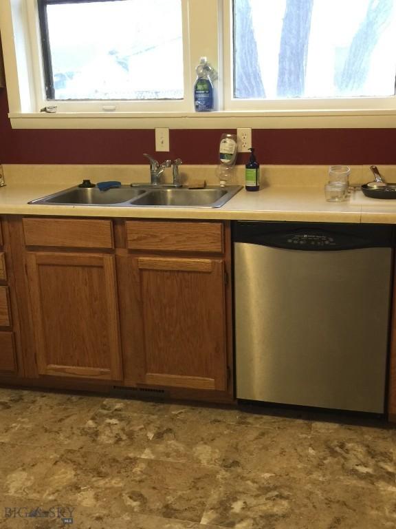 kitchen featuring a sink, a wealth of natural light, light countertops, and stainless steel dishwasher