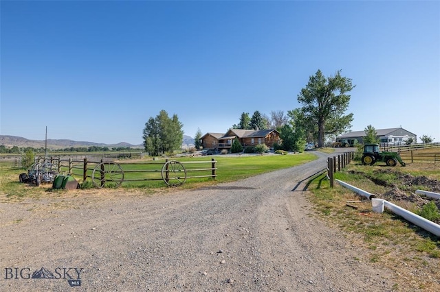 view of street with a rural view, a mountain view, and dirt driveway