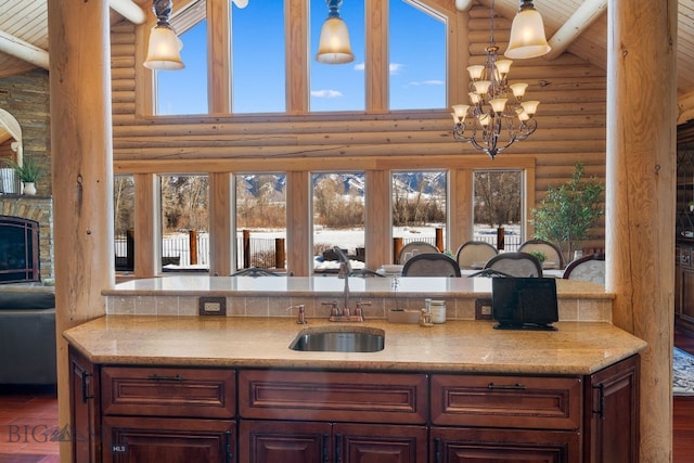 kitchen featuring light stone counters, a notable chandelier, a fireplace, open floor plan, and a sink