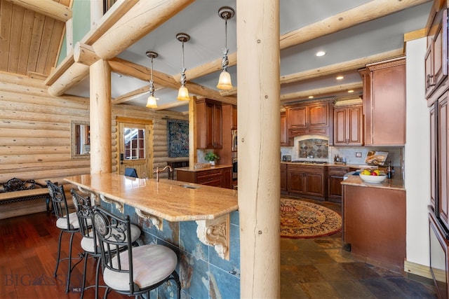 kitchen with a breakfast bar area, recessed lighting, a sink, beamed ceiling, and decorative light fixtures