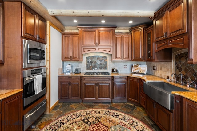 kitchen with a warming drawer, stainless steel appliances, a sink, and stone tile flooring