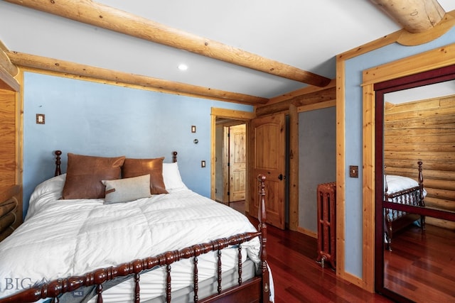 bedroom featuring beam ceiling, wood finished floors, and log walls