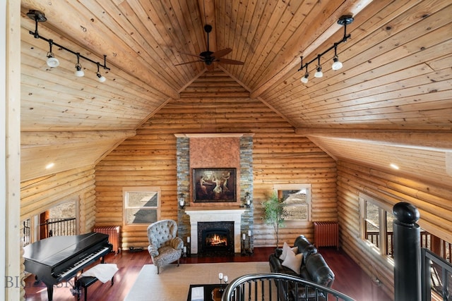 living area featuring a stone fireplace, hardwood / wood-style flooring, and rail lighting