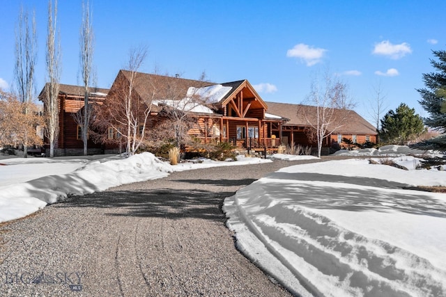 log home with a porch and gravel driveway