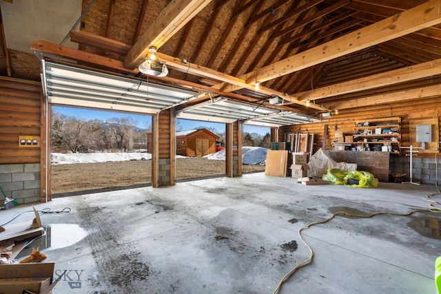 misc room featuring a garage, a wealth of natural light, electric panel, and vaulted ceiling