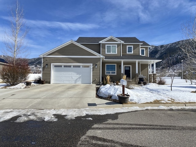 view of front facade with covered porch, driveway, a mountain view, and a garage