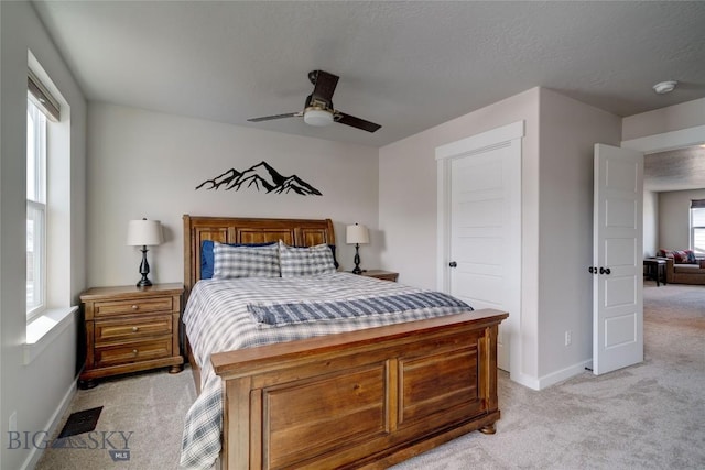 bedroom with baseboards, light carpet, a textured ceiling, and ceiling fan