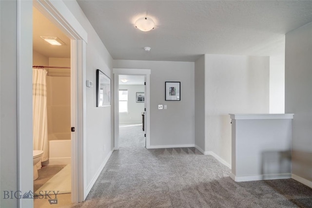 hallway featuring an upstairs landing, carpet flooring, and baseboards