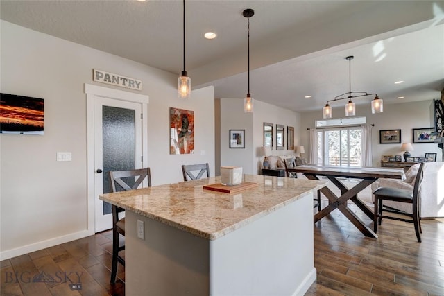 kitchen featuring dark wood finished floors, recessed lighting, baseboards, and a center island