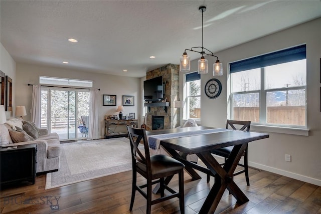 dining room with dark wood finished floors, a fireplace, baseboards, and a textured ceiling