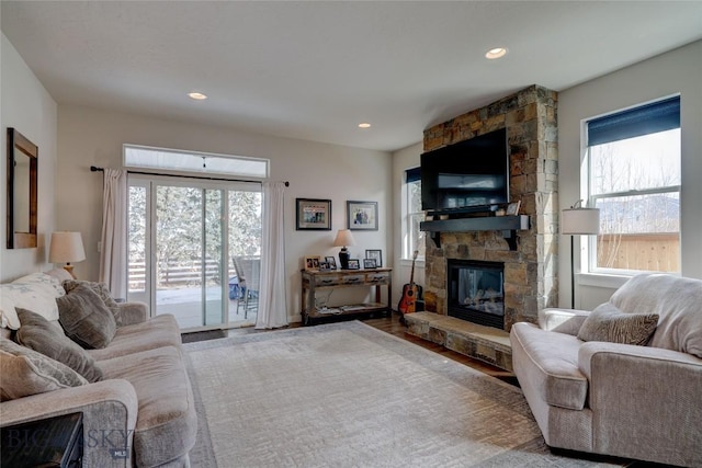 living room featuring a stone fireplace, recessed lighting, and wood finished floors