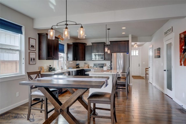 kitchen with dark brown cabinetry, appliances with stainless steel finishes, dark wood-style flooring, and light countertops