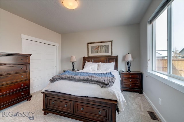 bedroom with visible vents, baseboards, light colored carpet, and a closet