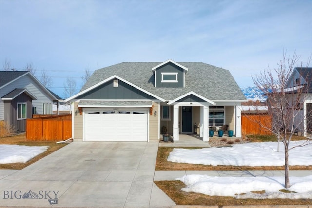 view of front of home with a shingled roof, board and batten siding, concrete driveway, and fence