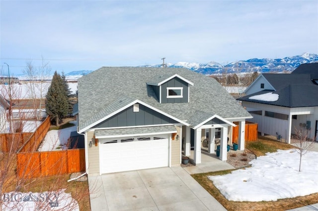 view of front of property with fence, a shingled roof, concrete driveway, a garage, and a mountain view