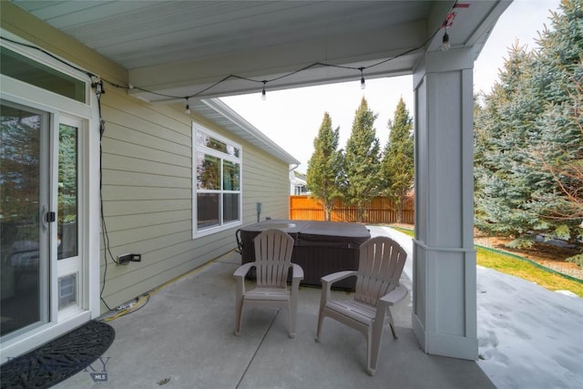 view of patio featuring fence and a hot tub