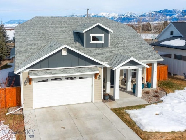 view of front of property featuring a mountain view, a shingled roof, an attached garage, and board and batten siding