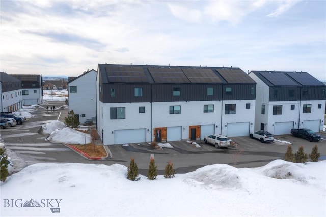 snow covered property with a residential view and a garage