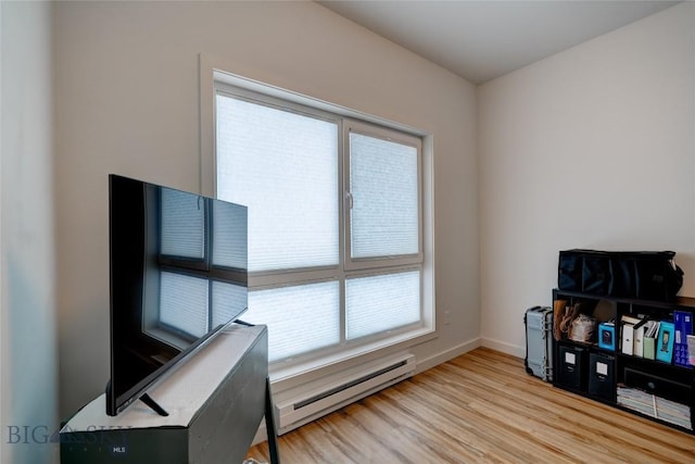 interior space with baseboards, baseboard heating, and light wood-style flooring