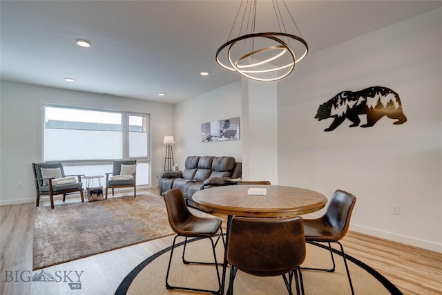 dining room with recessed lighting, baseboards, light wood-type flooring, and an inviting chandelier