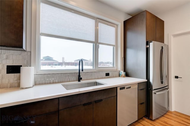 kitchen featuring a wealth of natural light, dishwashing machine, freestanding refrigerator, and a sink