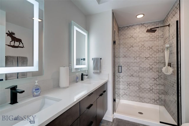 bathroom with double vanity, a shower stall, and a sink