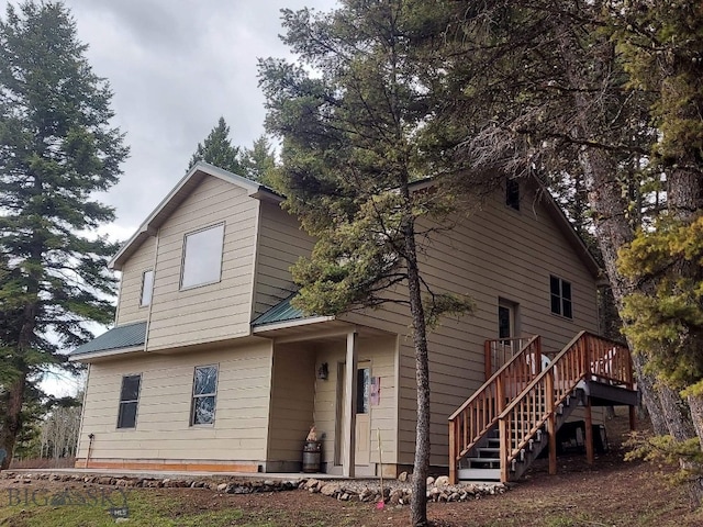 view of front of home with stairway, metal roof, and a deck