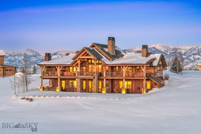 snow covered house with a mountain view and a chimney