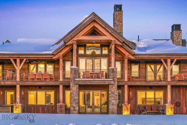 snow covered rear of property featuring french doors and a chimney