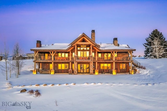 snow covered back of property featuring a chimney