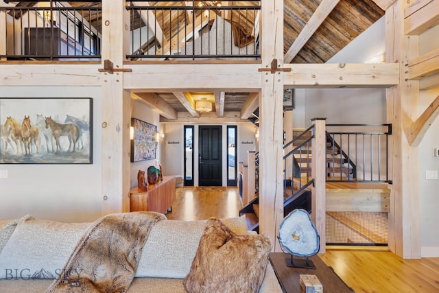 interior space featuring beam ceiling, stairway, a high ceiling, and wood finished floors