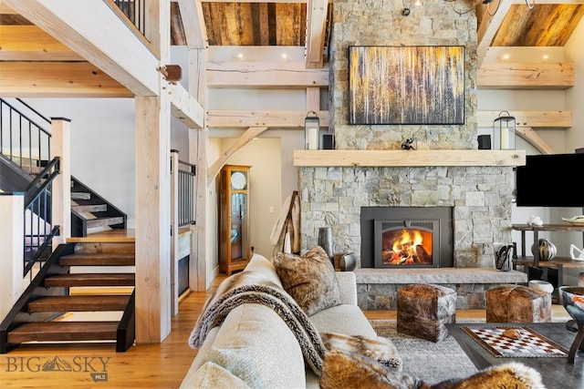 living room featuring stairs, a high ceiling, wood finished floors, and a fireplace