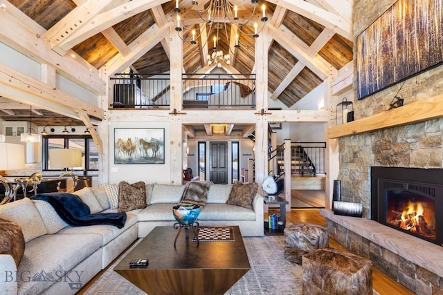 living room featuring wood finished floors, beam ceiling, a fireplace, and stairs