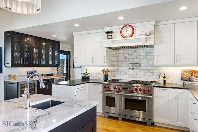 kitchen with a sink, white cabinetry, glass insert cabinets, and range with two ovens