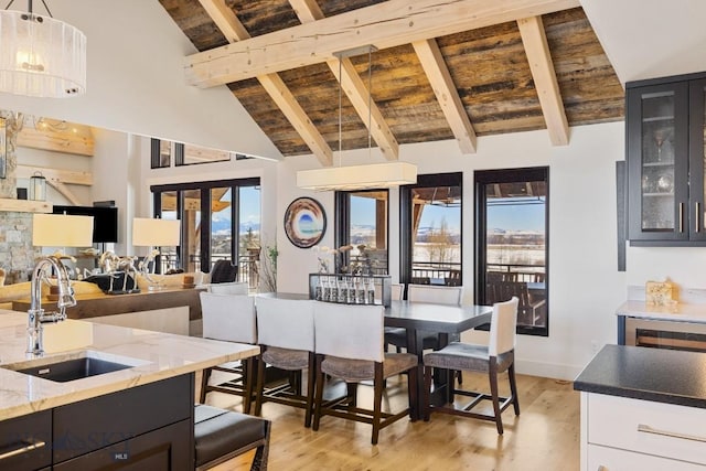 dining area featuring beamed ceiling, wood ceiling, light wood finished floors, and high vaulted ceiling