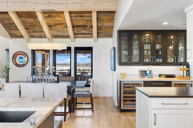 bar with light wood-type flooring, lofted ceiling with beams, recessed lighting, wine cooler, and indoor bar