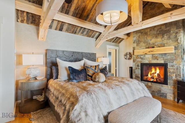 bedroom featuring wood finished floors, vaulted ceiling with beams, and a fireplace