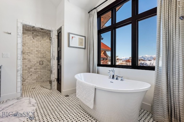 bathroom with a soaking tub, baseboards, and a stall shower