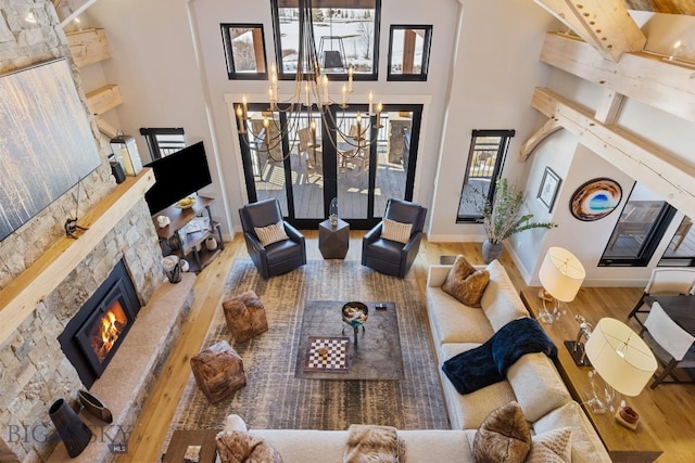 living room with a fireplace, a high ceiling, an inviting chandelier, and wood finished floors